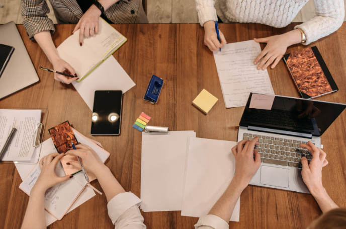 Conference room table with laptops, papers, and pencils, representing workplace stress, anxiety, and burnout for professionals in high-demand jobs.